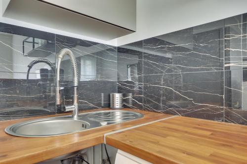 - une cuisine avec un évier et des murs en marbre noir dans l'établissement Cocooning Apt St Germain - 4 pers, à Paris