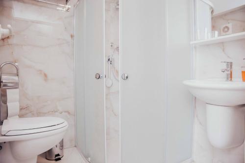 a white bathroom with a toilet and a sink at Shkodra apartment with amazing view in the city center in Shkodër