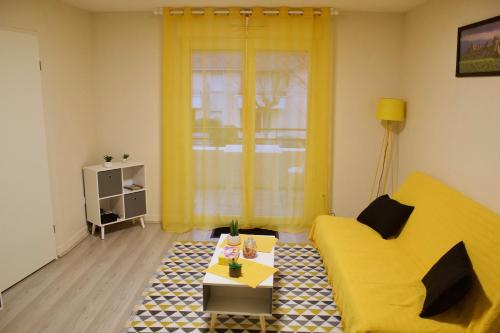 a living room with a yellow couch and a table at Appart Chrystal in Carcassonne