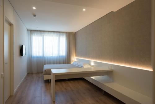 a bedroom with a bed with a desk and a window at Hotel Las Terrazas in Burgos