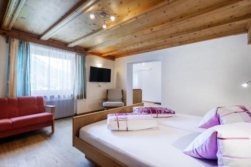a bedroom with a large bed and a chair at Hotel Chavalatsch in Tubre