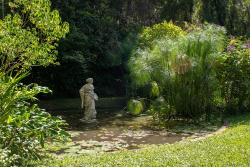 a statue in the middle of a pond in a garden at Pousada da Alcobaça in Itaipava