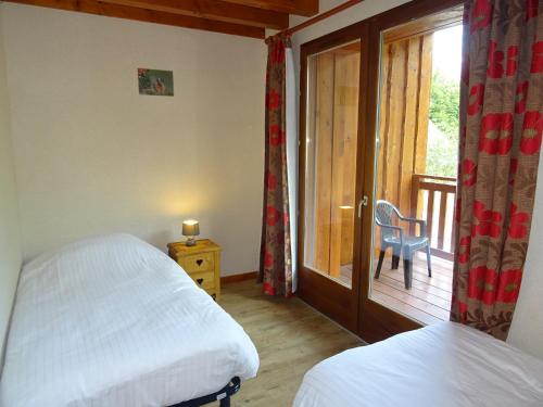a bedroom with two beds and a balcony with a window at Les Prés-Ronds in La Chapelle-en-Valgodemard