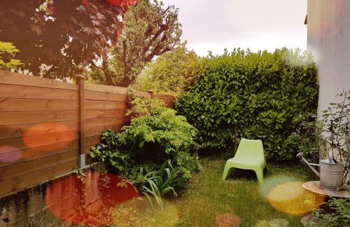 a green chair in a garden with a fence at gîte les petits poissons verts et massages in La Jarrie