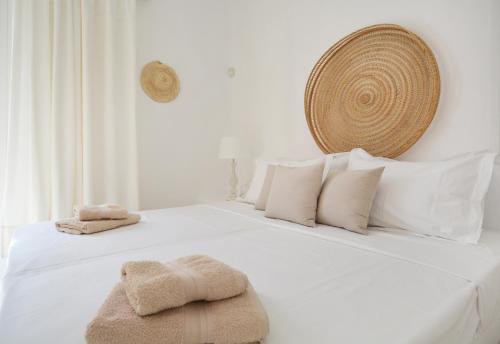 Una cama blanca con almohadas blancas y toallas. en Sea Breeze Mykonos, en Panormos  Mykonos