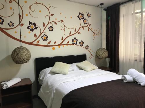 ein Schlafzimmer mit einem Bett mit einem Blumenbild an der Wand in der Unterkunft Posada J in Baños