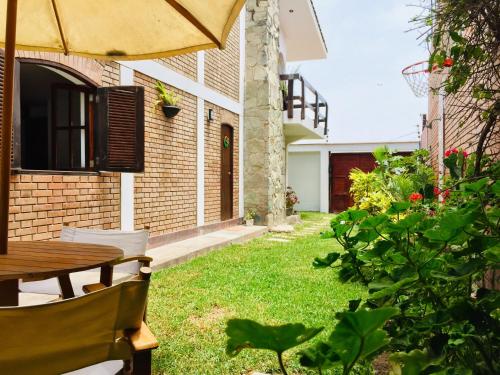 - un jardin avec une table en bois et un parasol dans l'établissement Casa de Playa Arica, à Lurín