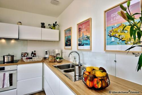 a kitchen with a sink and a bowl of fruit at Gîte Les Roseaux in Kerlouan