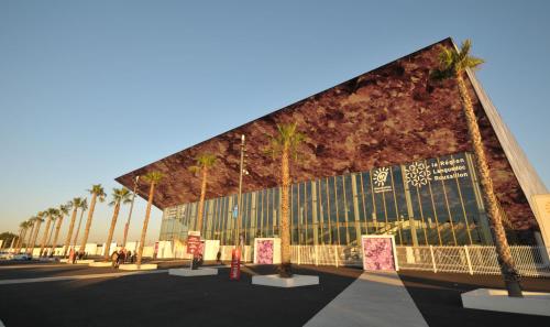 a large building with palm trees in front of it at Eurotel Parc Expo Airport Montpellier in Pérols