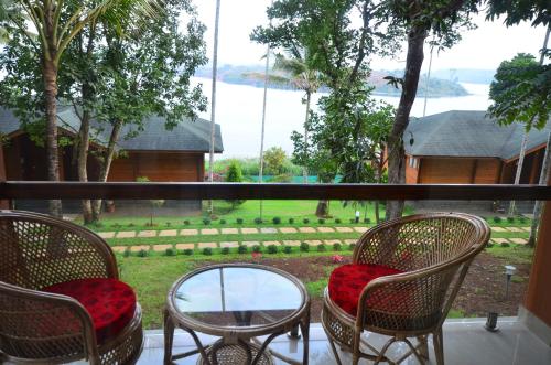 a balcony with chairs and a table and a view of a yard at LakeRose Wayanad Resort in Ambalavayal