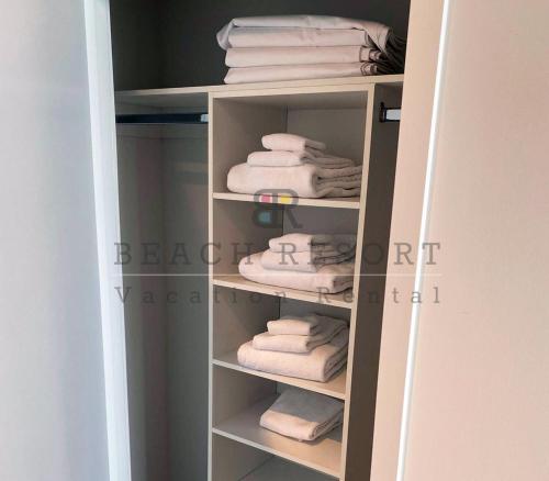 - un placard avec des serviettes blanches sur une étagère dans l'établissement HYDE Beach House Apartments, à Hollywood