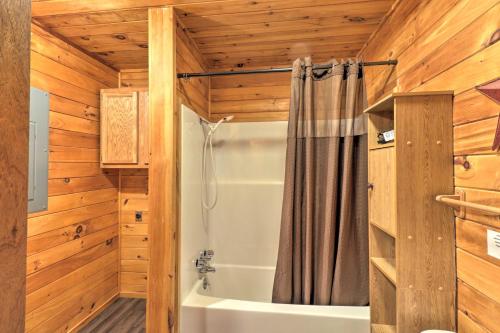 a bathroom with a bath tub and a shower curtain at Starstruck Cabin with Spa 4 Mi to Broken Bow Lake! in Stephens Gap