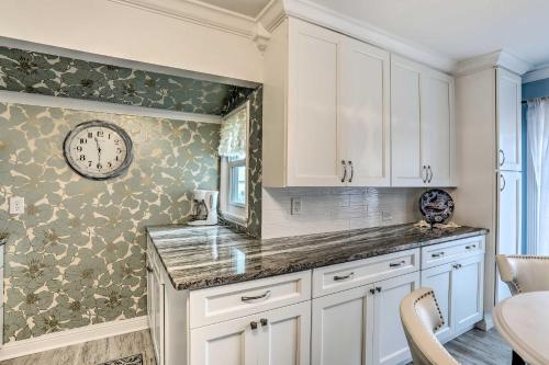 una cocina con armarios blancos y un reloj en la pared en Breezy Murrells Inlet Condo with Deck Walk to Beach, en Myrtle Beach