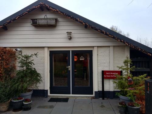 a white building with a door and some plants at De Oude Stoffeerderij in Dussen