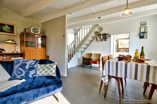 a living room with a table and a blue couch at Gîte Le pied à terre in Kerlouan