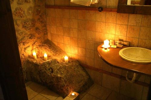 a bathroom with candles in a rock with a sink at Pigi Tarlampa Hotel in Ano Trikala