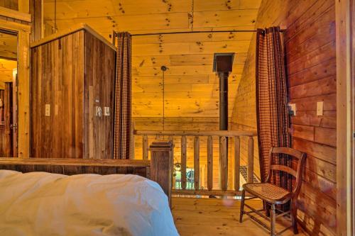 ein Schlafzimmer in einem Blockhaus mit einem Bett und einem Stuhl in der Unterkunft Scenic Log Cabin with Fire Pit and Stocked Creek! in Titusville