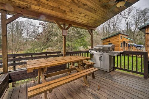 a picnic table and a grill on a wooden deck at Scenic Log Cabin with Fire Pit and Stocked Creek! in Titusville