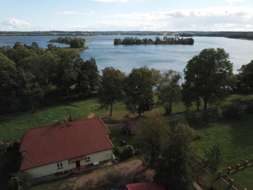 a house with a red roof next to a river at Złota Leśniczówka in Rydzówka