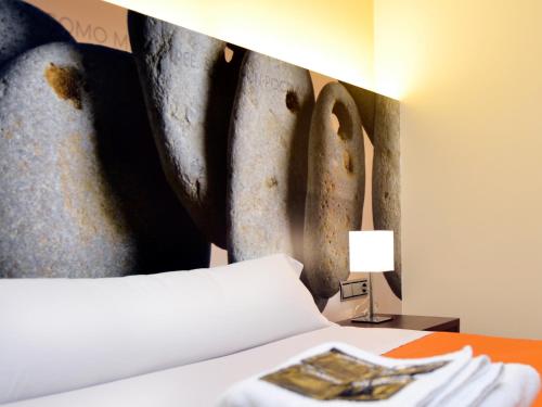 サモラにあるHostal Bajo La Murallaのベッドルーム1室(壁に絵画が描かれたベッド1台付)