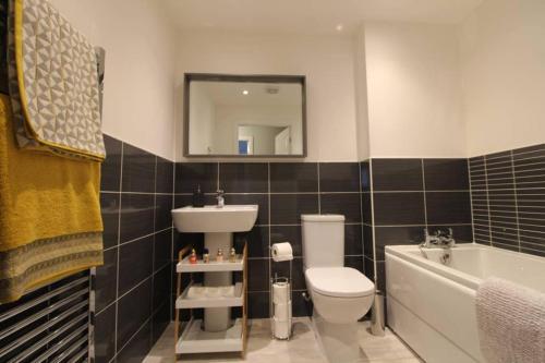 a bathroom with a sink and a toilet and a bath tub at Llys Marina in Y Felinheli