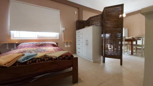 un dormitorio con una cama y una ventana y una mesa en el Depto Villa Gesell en Villa Gesell