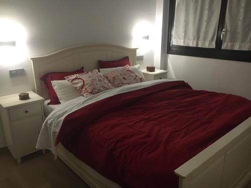 a bedroom with a large bed with red sheets and pillows at Urrumendi in Mungia