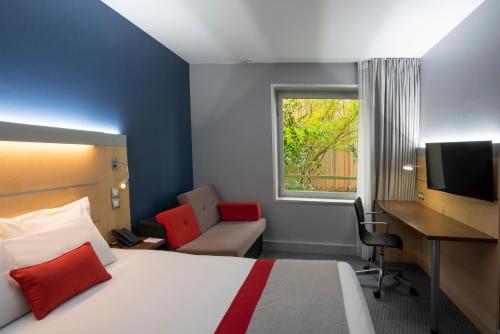 a bedroom with a bed and a desk and a computer at Holiday Inn Express Paris-Canal De La Villette by IHG in Paris