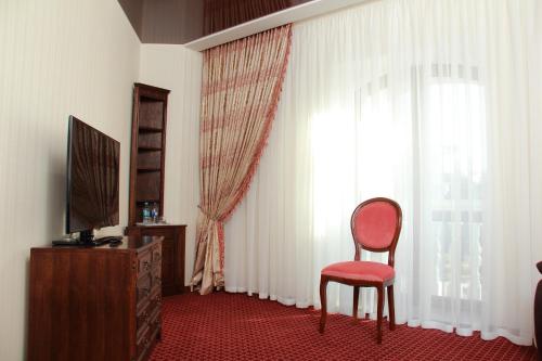 a room with a red chair and a window at Hotel Aristokrat in Poltava