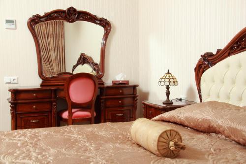 a bedroom with a bed and a mirror and a chair at Hotel Aristokrat in Poltava