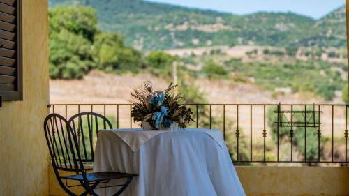 a table with a white table cloth and chairs on a balcony at Agriturismo Carrucana in Martis