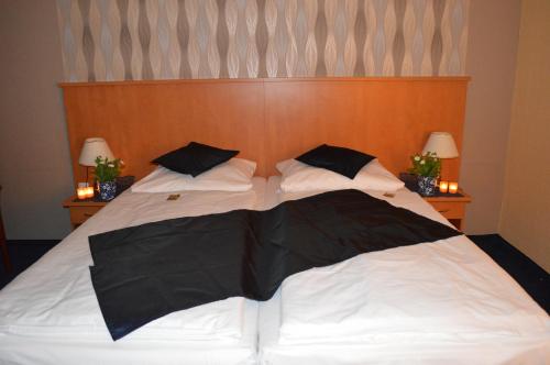 a bed with two black and white pillows on it at Hotel Royal Hanau in Hanau am Main