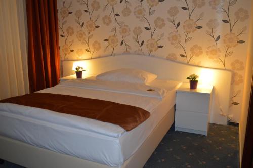 a large bed in a bedroom with a wall with flowers at Hotel Royal Hanau in Hanau am Main