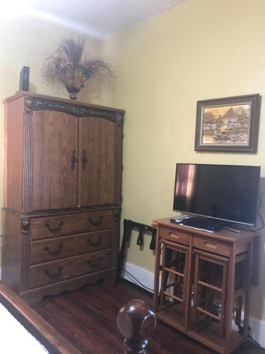 a living room with a television and a wooden cabinet at Charming Historic Downtown Apartment in St. Augustine
