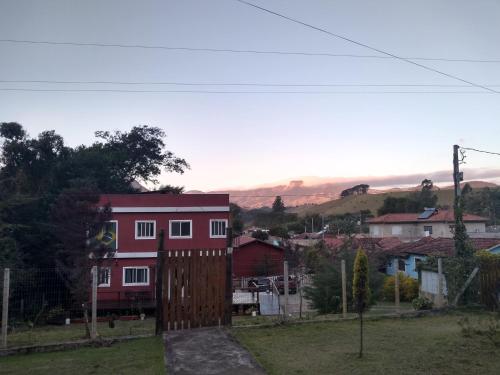 a red house with a wooden gate in a village at Quarto Aconchegante in São Bento do Sapucaí