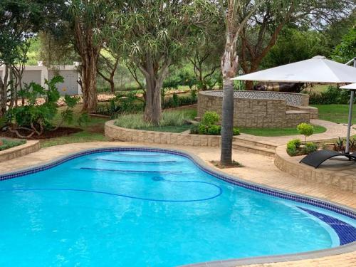 a large blue swimming pool in a yard with trees at La Fiato Luxury Lodge in Dalmada AH