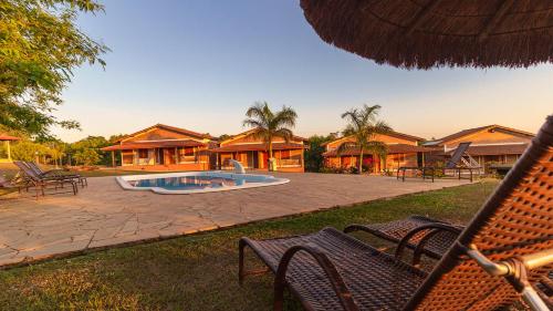 a patio with chairs and a swimming pool and houses at Rancho da Cachaça Pousada in Holambra