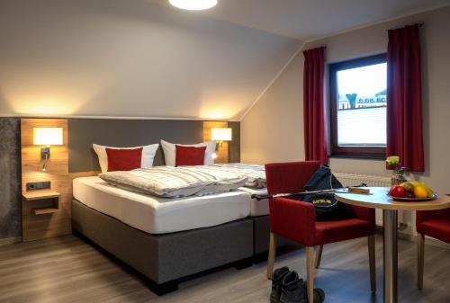 une chambre d'hôtel avec un lit, une table et des chaises dans l'établissement Restaurant - Pension Im Pfenn, à Irrhausen