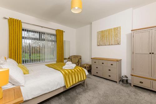 a bedroom with a bed and a window with yellow curtains at Park View - 4 Star Luxury in Belfast