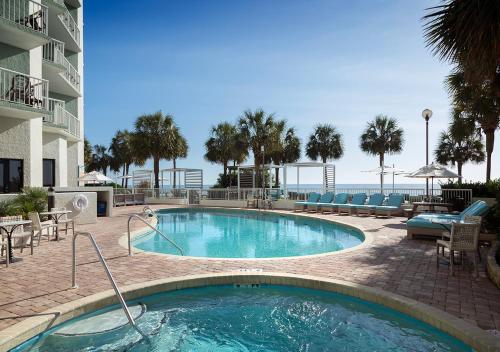 a swimming pool in a resort with chairs and the ocean at The Strand - A Boutique Resort in Myrtle Beach