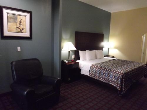 a hotel room with a bed and a chair at Sunriser Inn in Kilgore