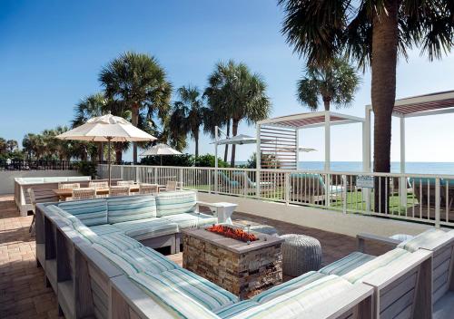 a patio with a couch and tables and the beach at The Strand - A Boutique Resort in Myrtle Beach