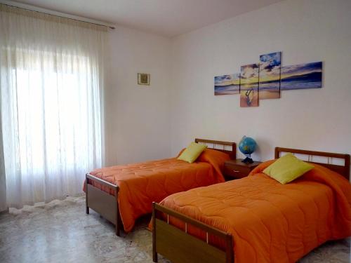 - 2 lits dans une chambre avec des draps orange dans l'établissement Appartamento Vela Azzurra, à Peschici