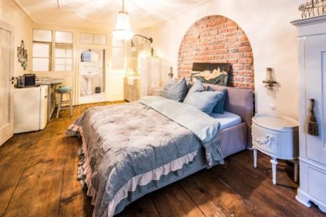 a bedroom with a large bed with a brick wall at Pension Chapeau in Landsberg am Lech