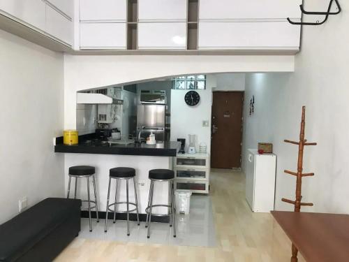 een keuken met een aanrecht en krukken in een kamer bij Ótimo Conjugado - Estúdio - Praia do Flamengo - RJ in Rio de Janeiro