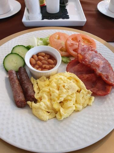 a plate of breakfast food with sausage eggs potatoes and beans at Harmony Guesthouse in Nelspruit