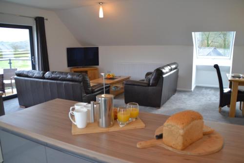 a living room with a table with bread and orange juice at Gerycastell Luxury Holiday Apartment with Stunning Views & EV Station Point in Carmarthen