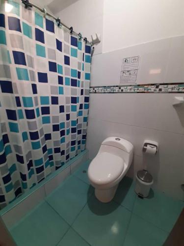 a bathroom with a toilet and a shower curtain at Hotel Ocean Beach Paracas in Paracas