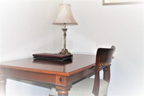 a desk with a lamp and a chair at Cotswold Gardens in Armidale