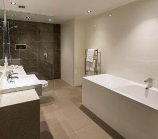a bathroom with a tub and a sink and a toilet at Waipuna Hotel & Conference Centre in Auckland